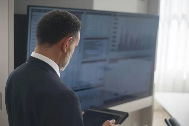 Business professional analyzing financial metrics on a large screen to ensure Accurate Data Entry.