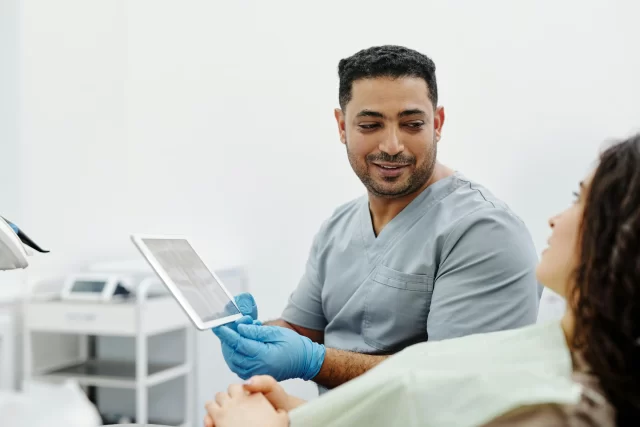 A dentist explains a digital scan to a patient, demonstrating a Customer-Centric approach to dental care.