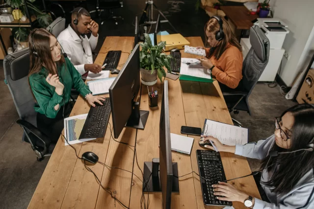 Customer support team working at a shared office desk as part of Business Function Outsourcing.
