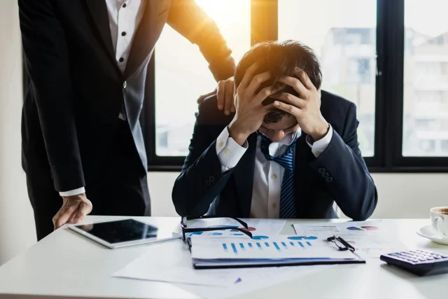 Stressed professional overwhelmed by data reports at an MTM pharmacy.
