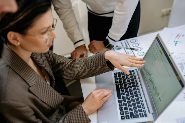 Business professionals collaborating on a laptop to analyze data trends for Health and Information Management.