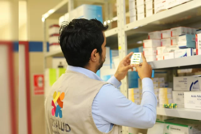 Pharmacy worker stocking medication in a healthcare facility to support PBM Pharmacy Benefit Manager operations.
