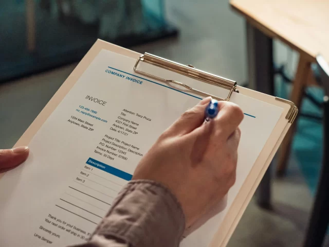 A person reviewing a professional invoice on a clipboard to oversee management in health information.