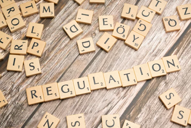 Scrabble tiles on a wooden surface spelling Regulation, illustrating management in health information.