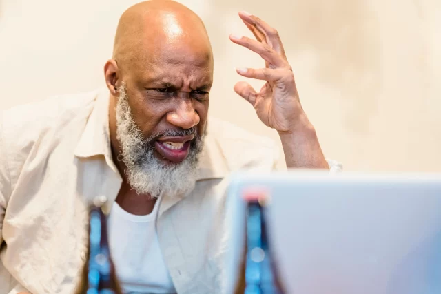 Frustrated senior professional looking at a laptop while working as one of the Managers for pharmacy benefit.