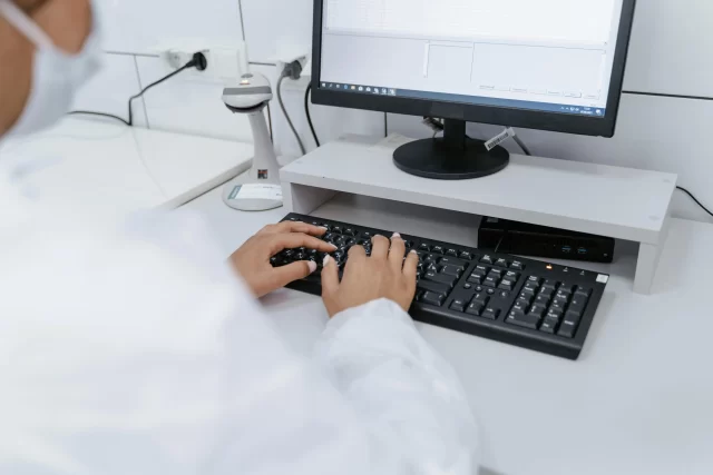 A medical professional typing on a keyboard, facilitating efficient management for health information.