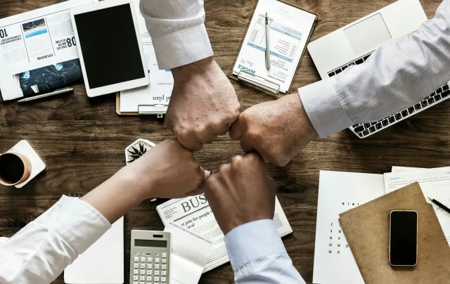 Diverse professionals perform a fist bump over a desk, representing the Electronic prescription service in Switzerland.