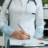 Doctor holding a clipboard and writing notes to manage an electronic prescription service in Switzerland.