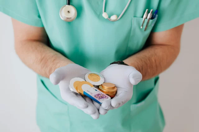 Medical professional holding chocolate coins and a simulated 500-euro note to symbolize healthcare operations cost reduction.