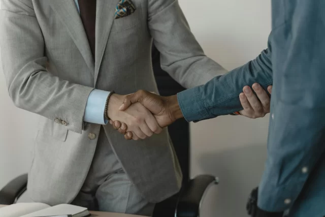 Two professionals in business attire shaking hands to signify a successful partnership for Benefit Managers.