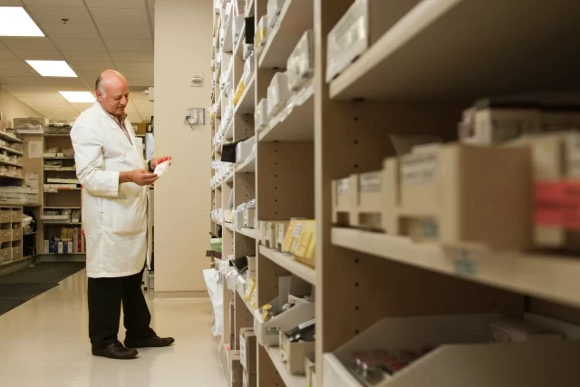 A pharmacist inspecting medication packaging, highlighting efficient Product Information Management for Swiss Pharmacies.