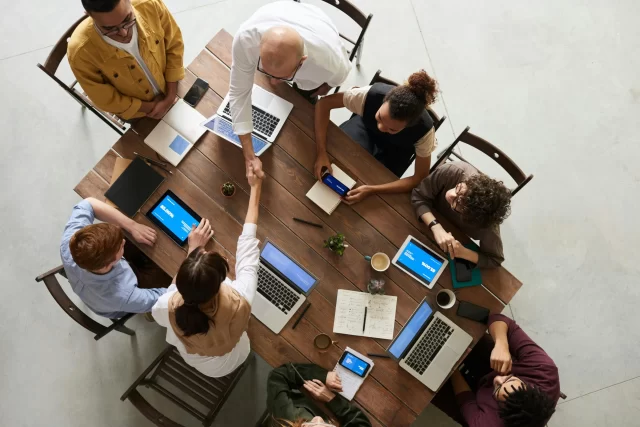 A diverse team collaborates around a table to discuss Product Information Management for Swiss Pharmacies.